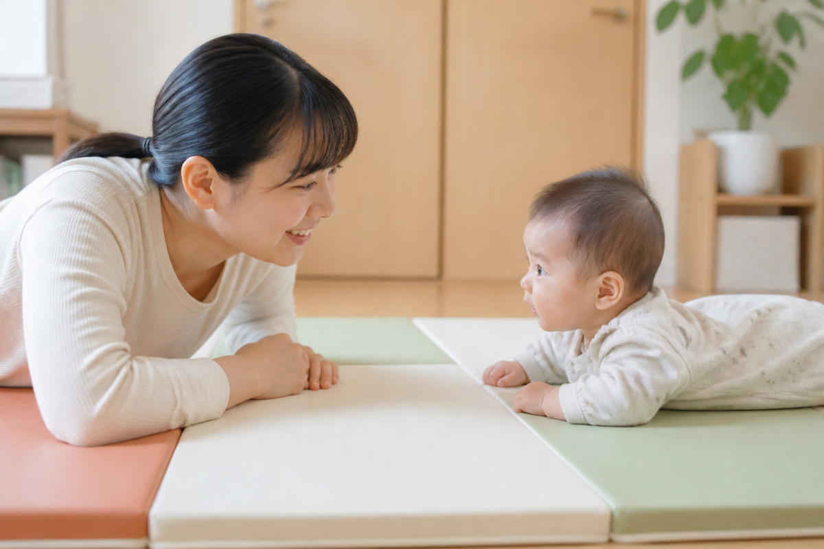 保護者が目線を合わせて見守る中でタミータイムをする赤ちゃん